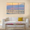 People enjoying themselves and swimming in the sea during sunset multi panel canvas wall art