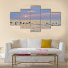 People enjoying themselves and swimming in the sea during sunset multi panel canvas wall art